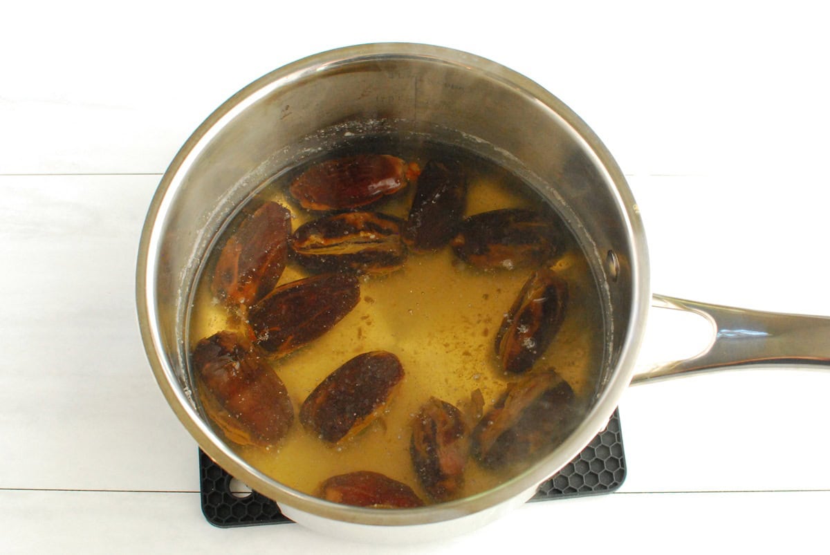 Dates soaking in hot water in a pot.