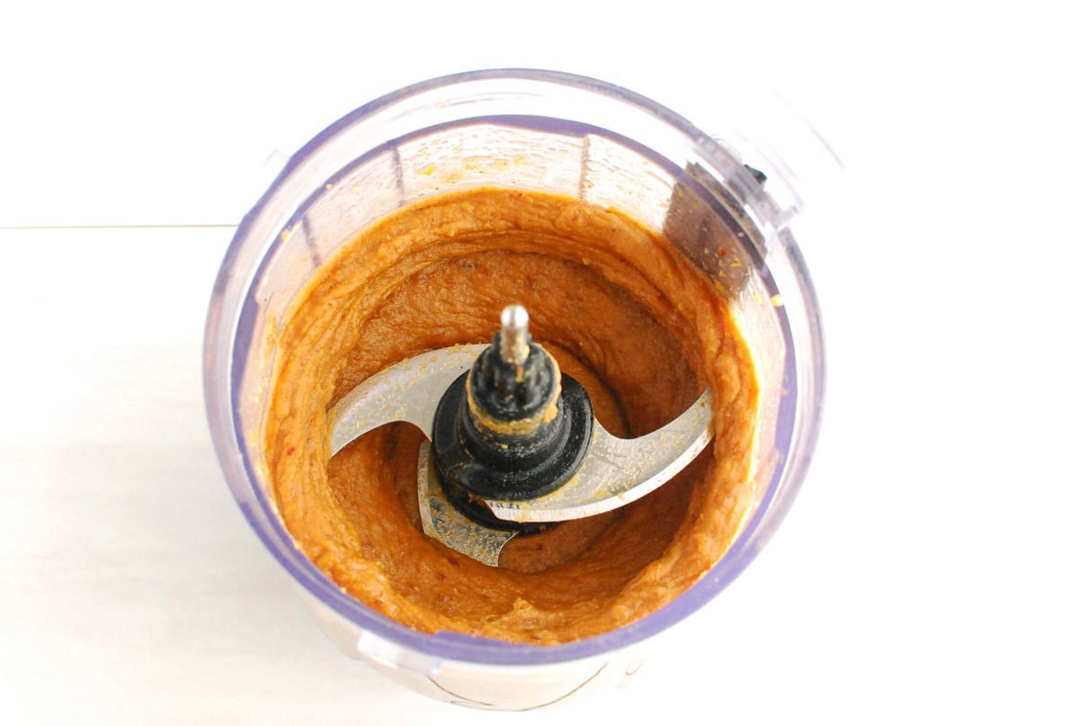 A mini food processor bowl with the mixture of dates, sweetpotato, almond butter, coconut oil, and salt.