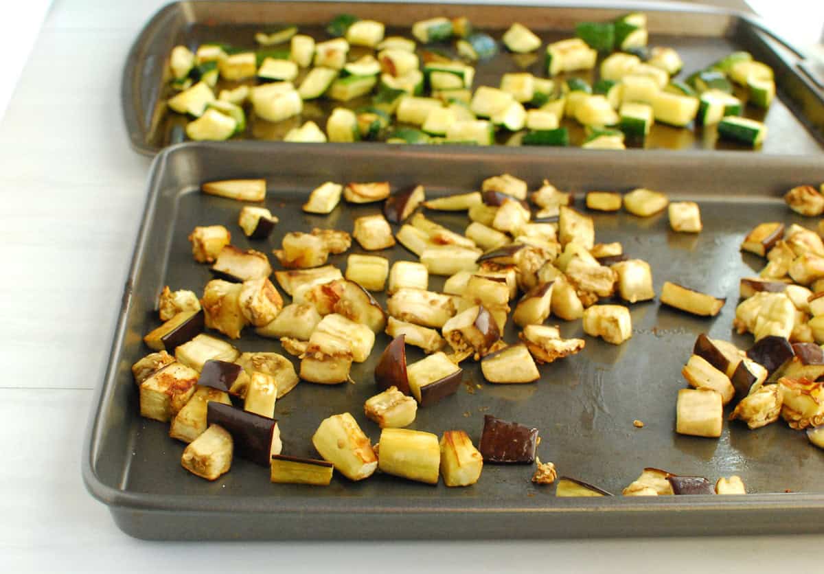 Two baking sheets with roasted eggplant and roasted zucchini.